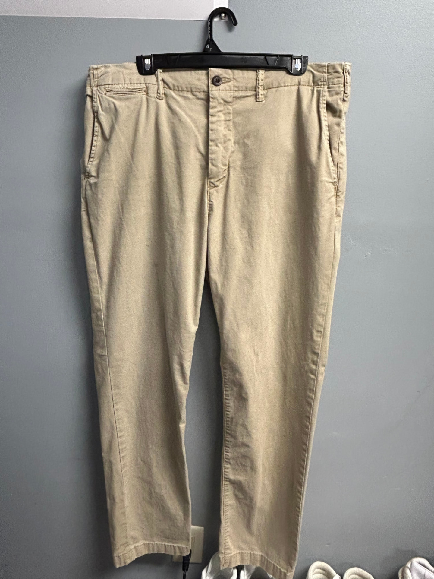 Tan khaki chino pants on a hanger