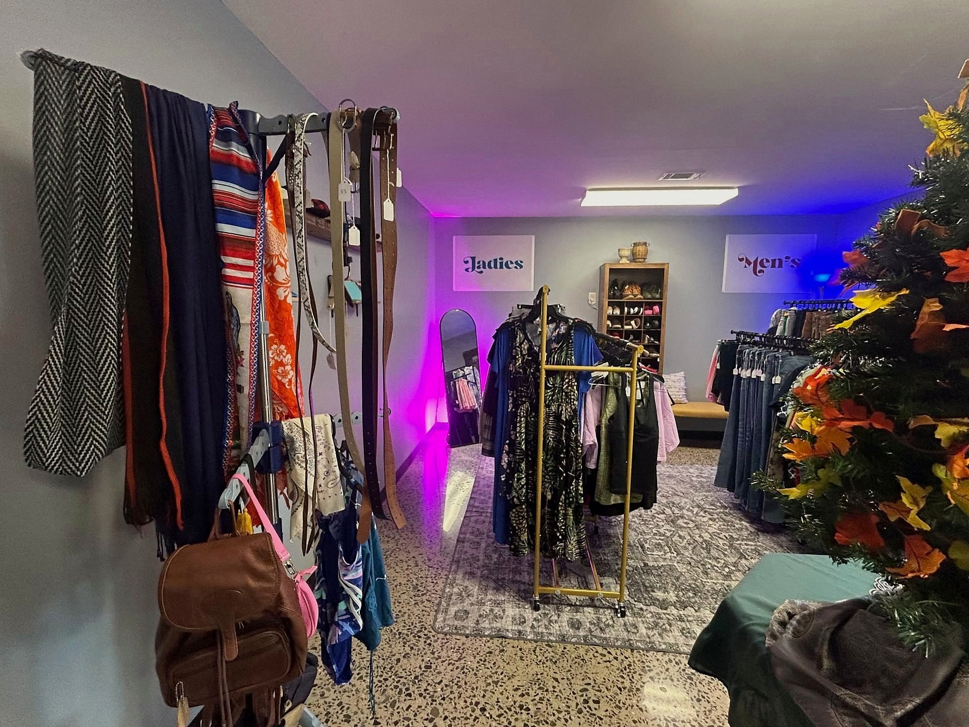 Racks of vintage scarves, belts, dresses, and men's jeans under Ladies and Men's signs