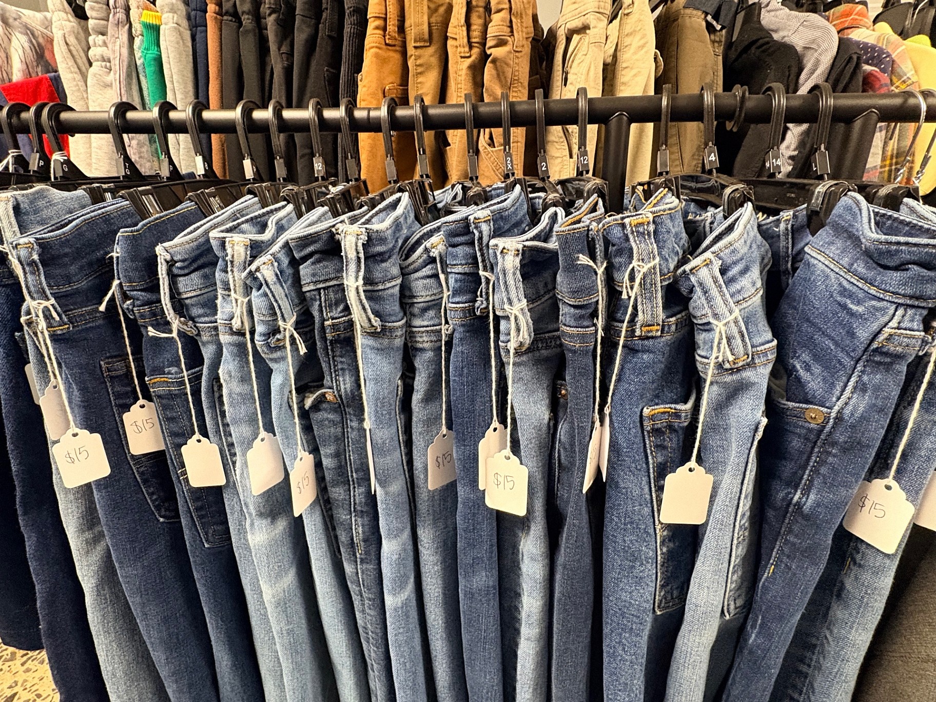 Rack of vintage denim jeans with handwritten price tags at Ozark Vintage Thrift Works