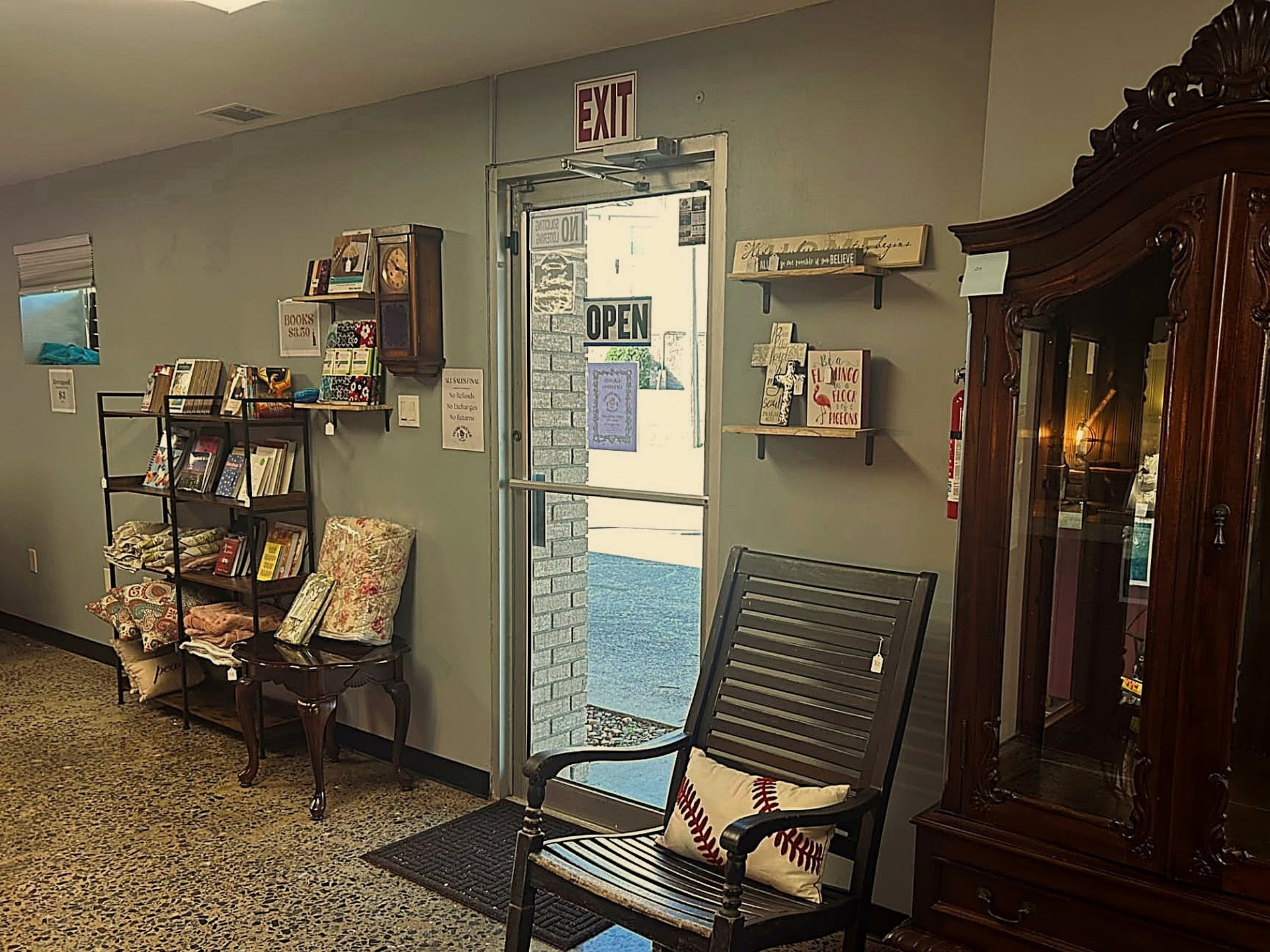 Antique cabinet, rocking chair, books, and home décor near the entrance of Ozark Vintage Thrift Works