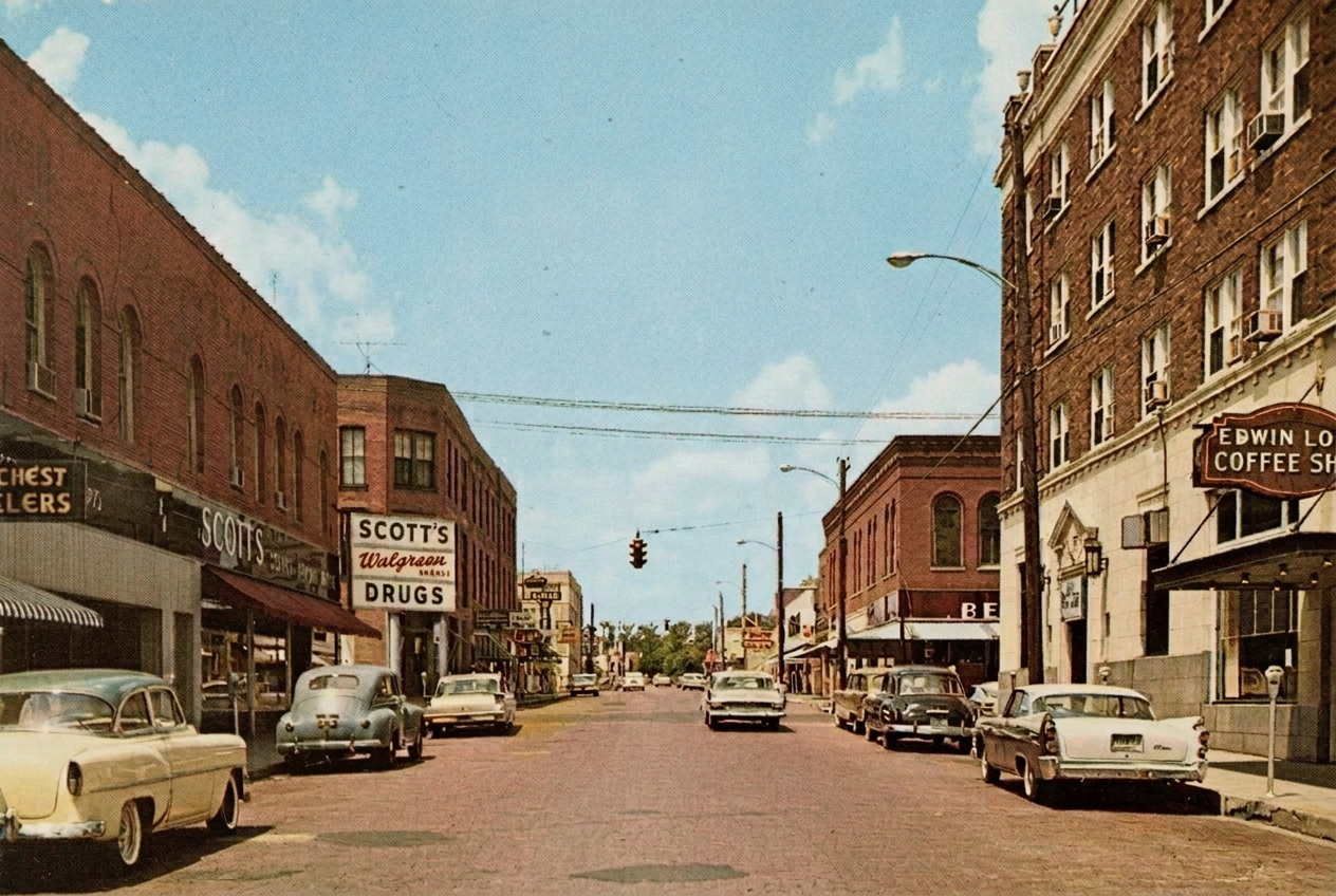 Vintage color postcard of Pine Street showing classic storefronts and cars from mid-century Arkansas